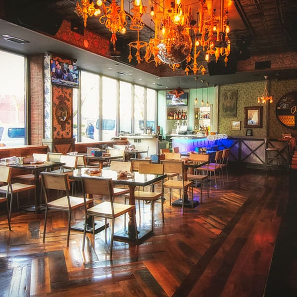 The White Bull Tavern's dining area features a bar with blue lighting, tables, and ornate chandeliers.