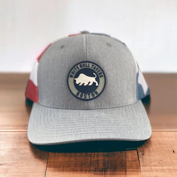 Gray White Bull Tavern baseball cap with a bull logo on a wooden surface.