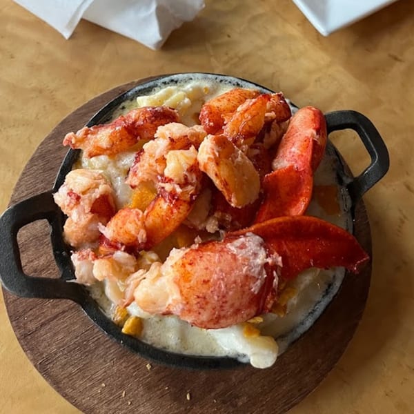 Lobster mac and cheese in a cast iron skillet on a wooden board at The White Bull Tavern.